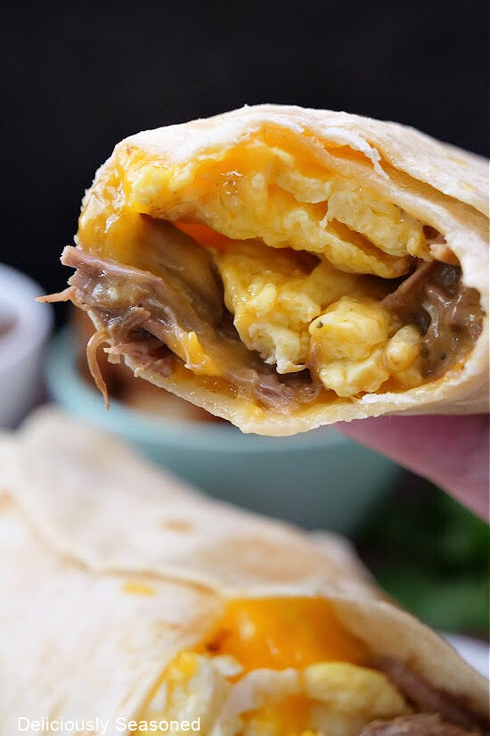 A close up of a breakfast burrito with a bite taken out of it.