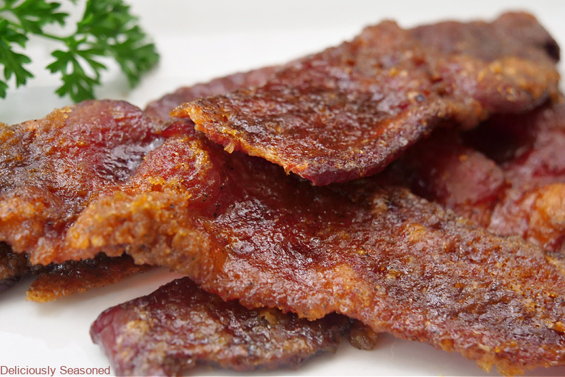 A few pieces of candied smoked bacon on a white plate.