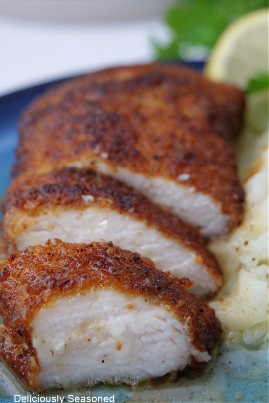 A close up picture of a piece of chicken cut into slices and covered in lemon glaze.