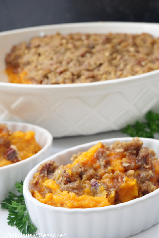 Three white oval bowls with sweet potato casserole in them.