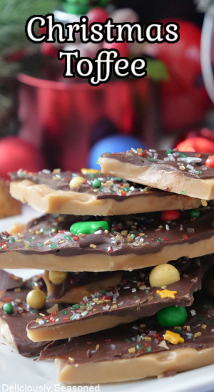 A white plate with a stack of toffee pieces on it decorated with chocolate and holiday sprinkles.