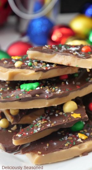 A close up of a stack of toffee that is broke into pieces and decorated with chocolate and holiday sprinkles.