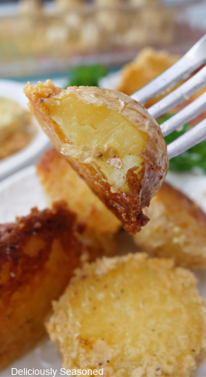 A close up of a bite of a garlic parmesan potato on a fork.