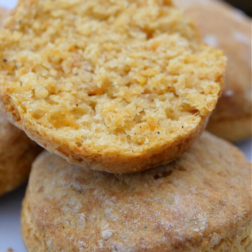 A sweet potato biscuit split in half on top of another one that's whole on a plate.