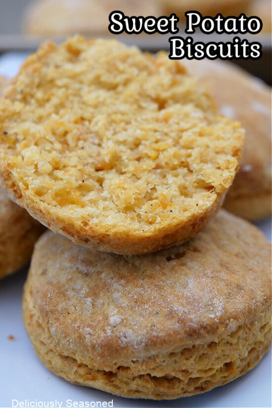 A close up of a couple sweet potato biscuits with one cut in half and showing the inside of the biscuit.