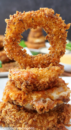 A stack of crispy onion rings on a white plate.