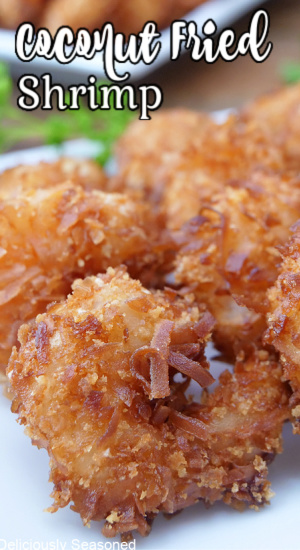 A close up of a few pieces of coconut shrimp on a white plate with the title of the recipe at the top of the photo.
