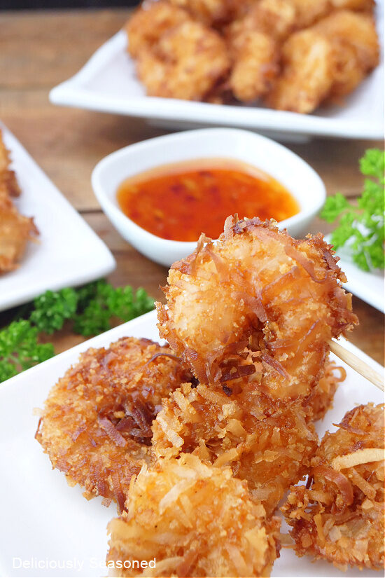 Six pieces of coconut shrimp on a white plate.