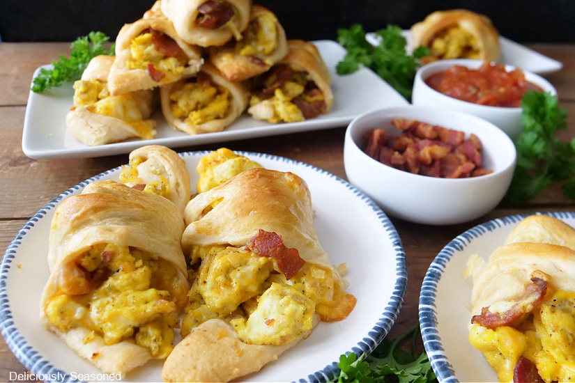 A horizontal photo of crescent roll breakfast crescents on white plates.