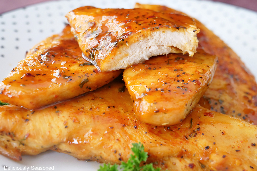 a horizontal photo of a white plate with a stack of thin sliced chicken breasts on it.
