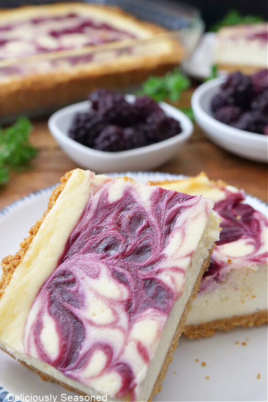 Two blackberry cheesecake bars  on a white plate.