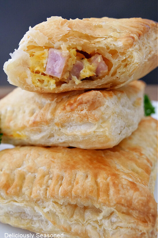 A stack of breakfast turnover on a white plate with a big bite taken out of the top one. 