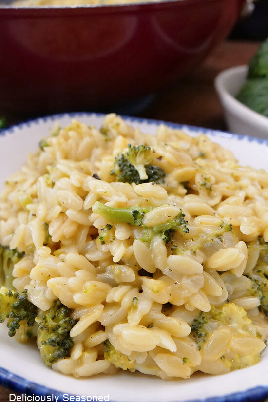 A close up of a serving of cheesy orzo pasta with broccoli.