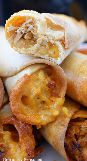 A close up of a stack of flautas with a bite taken out of one of them.