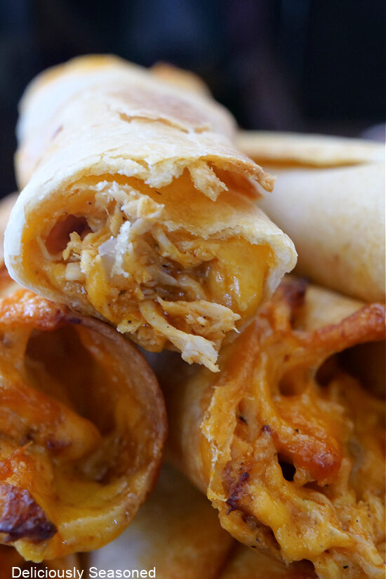 A super close up photo of a buffalo chicken flauta showing the chicken and cheese on the inside.
