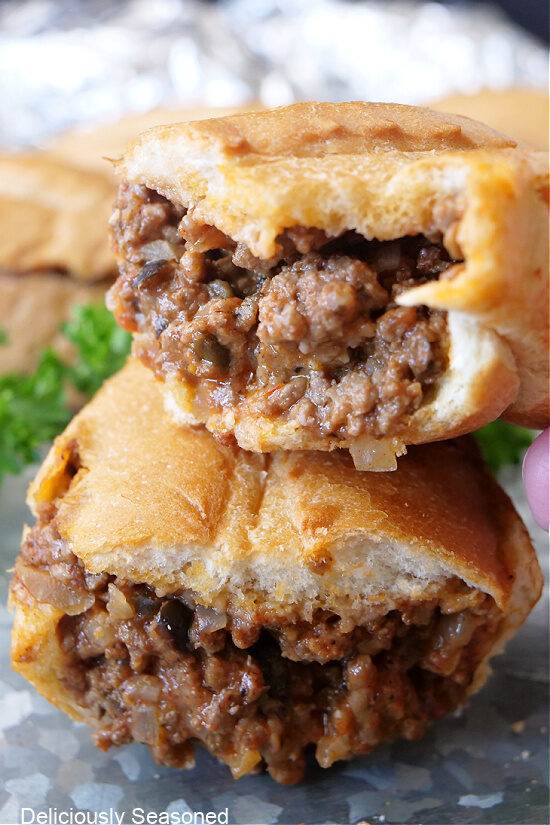 A close up of two halves of a cheesy beef sandwich with one on top of the other.
