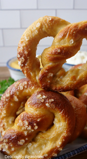 A pretzel being held up over a plate of pretzels. 