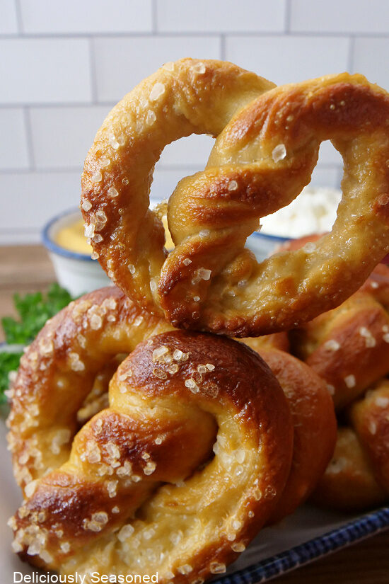 A handful of soft pretzels on a white plate with blue trim. 