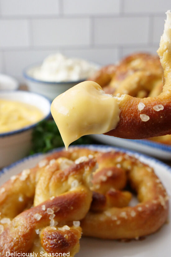 A piece of pretzel dipped in cheese dip.