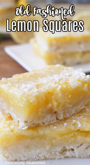 A close up of two lemon squares on a white plate.