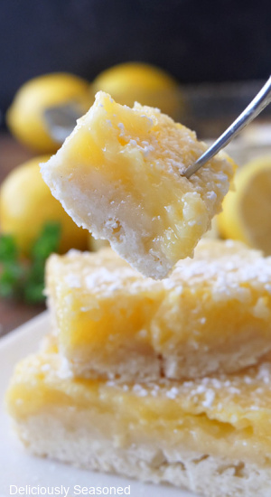 A close up photo of a bite of lemon squares on a fork.