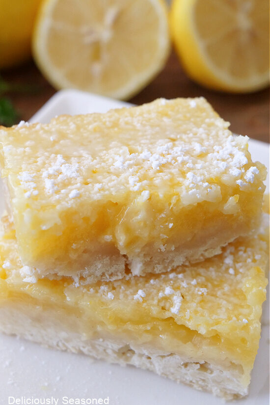 A close up of two old fashioned lemon squares on a white plate.