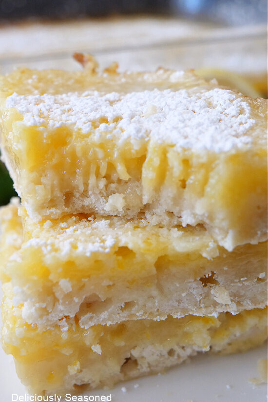 A close up of a three lemon squares stacked on top of each other.
