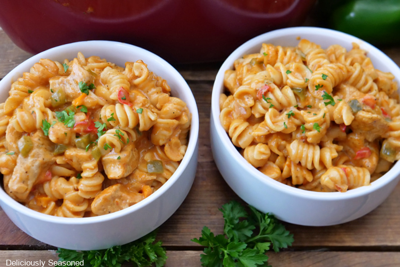 A horizontal photo of two white bowls filled with creamy chicken pasta side by side.