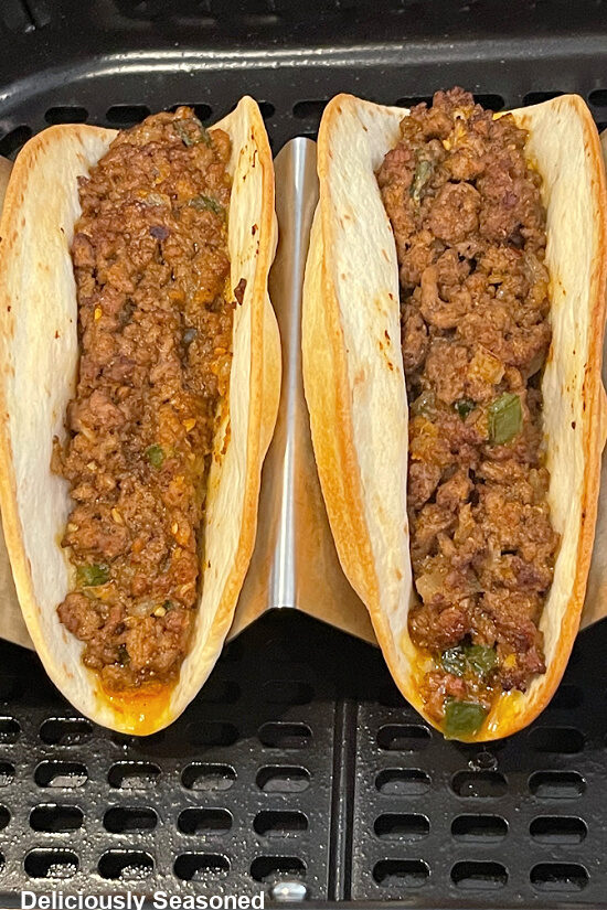 Two flour tortillas filled with ground beef after being air fried.