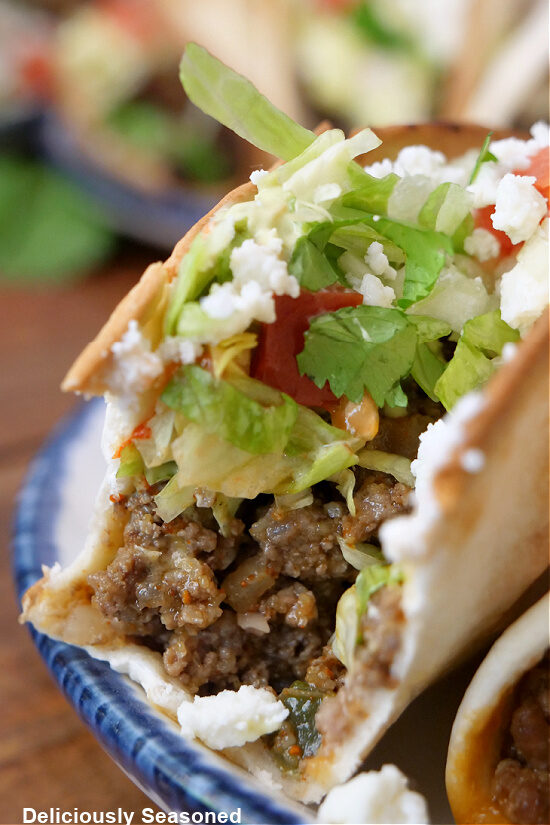 A close up of a ground beef taco with a big bite taken out of it.