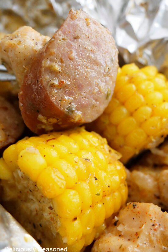 A close up photo of corn on the cob and sliced smoked sausage.