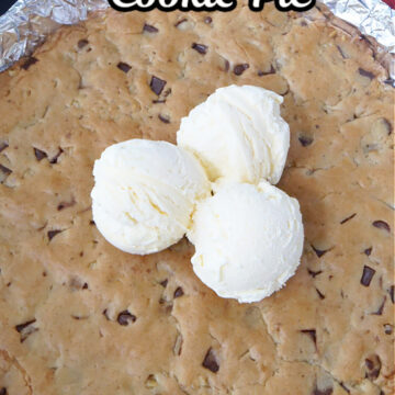 An oven baked skillet chocolate chip cookie pie with three scoops of vanilla ice cream on it.