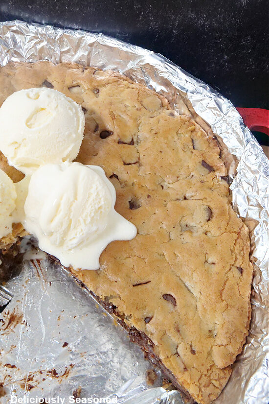A skillet cookie pie with a slice taken out of it.