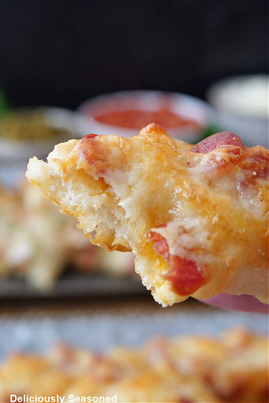 A close up of a pizza breadstick with a bite taken out of it.