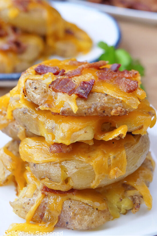 Four flattened baby potatoes with cheese and bacon on them.