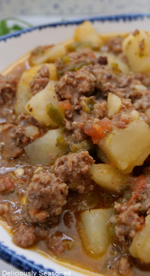 A white bowl with blue trim filled with a serving of ground beef and potatoes.