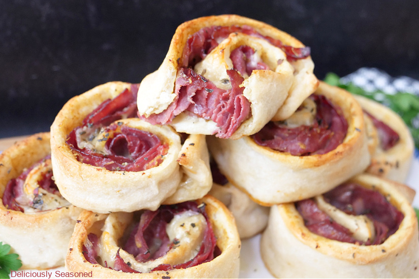 A horizontal photo of a plate full of pastrami and swiss pinwheels.