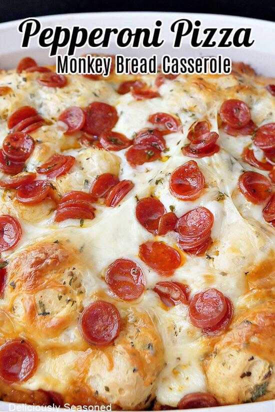 A white casserole dish filled with pizza monkey bread with mini pepperonis.