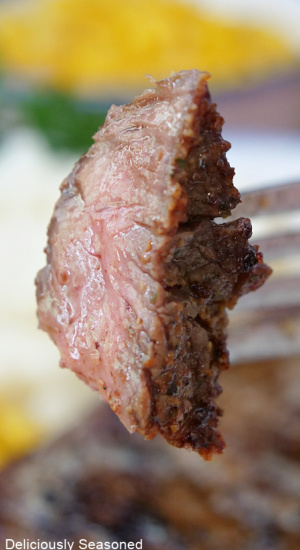 A close up of a bite of steak on a fork.