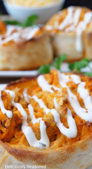 A close up of a pinwheel medallion filled with shredded chicken, buffalo sauce and drizzled with ranch dressing.