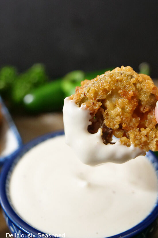 A single crispy jalapeno slice that has been dipped in ranch dressing.