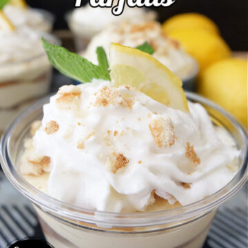 A small parfait cup filled with lemon pudding, lemon wafers, topped with whipped cream and a slice of lemon.