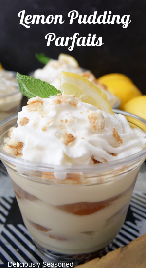 A close up of lemon pudding with lemon wafers and whipped cream in a small parfait cup.