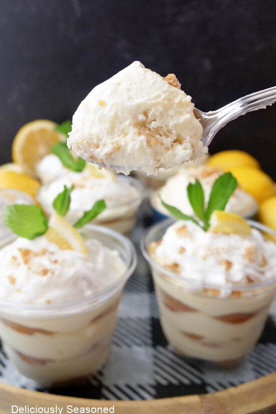 A spoonful of lemon pudding held over a few parfait cups filled with lemon pudding.