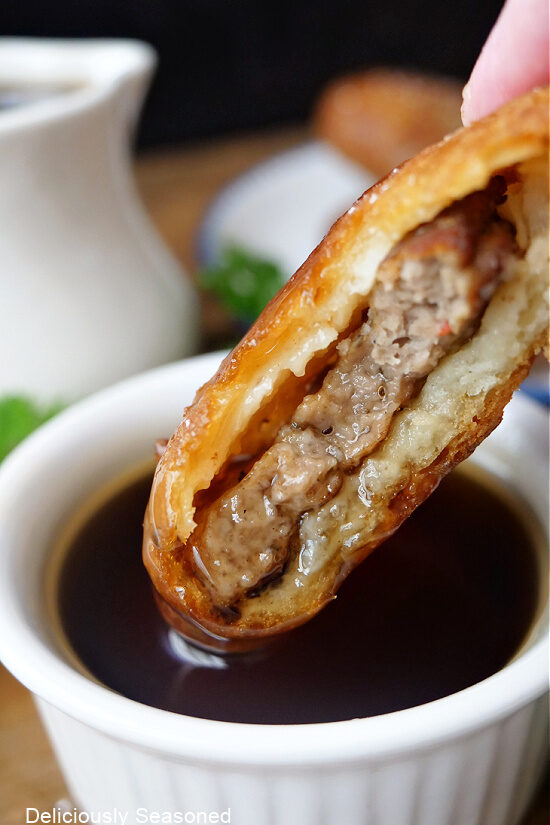 A pancake sausage bite being dipped into a small bowl of syrup.