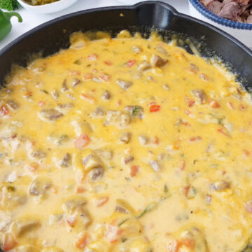 A white cast iron skillet filled wih brisket queso.