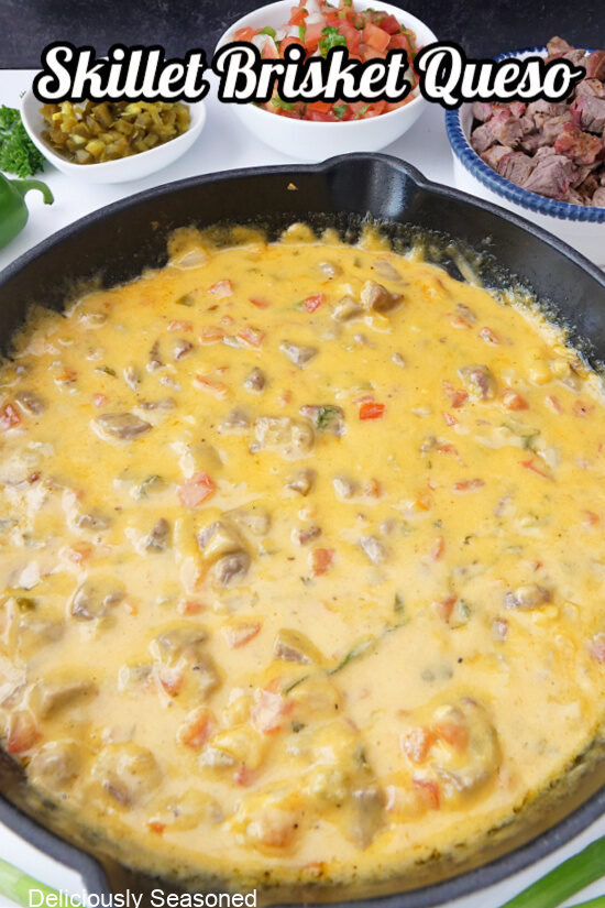 A white cast iron skillet filled wih brisket queso.
