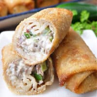 A close up of two egg rolls with one of them cut in half.