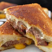 A close up of a grilled sandwich stuffed with leftover brisket, two types of cheese.