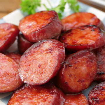 A light blue and white checkered plate with sliced smoked sausage on it.